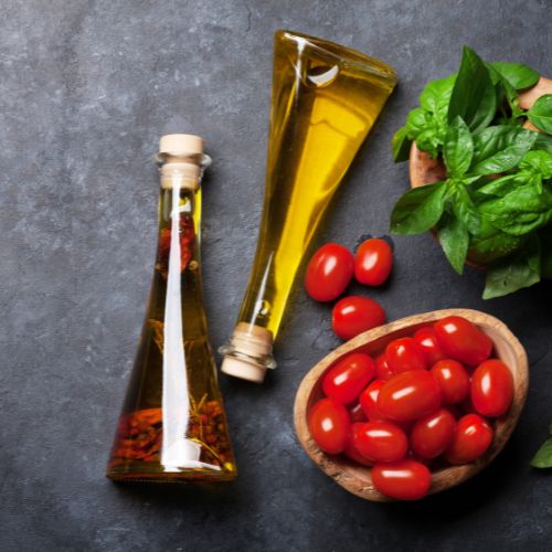 Photo of bottles of olive oil with a bowl of tomatoes